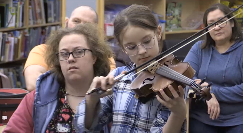 A young girl learns how to play the violin during a new class offered by Glowing Hearts Charity on Wed. Feb. 21, 2024 (CTV News/Dave Sullivan). 