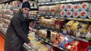 NDP Leader Jagmeet Singh points to a $20 package of cheese during a visit to a Loblaws grocery store in Ottawa on Wednesday, Feb. 21, 2024. THE CANADIAN PRESS/Mickey Djuric