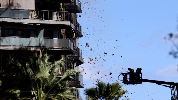 Debris falling on firefighters as they work at a burned block building in Valencia, Spain, Friday, Feb. 23, 2024. (AP Photo/Alberto Saiz)