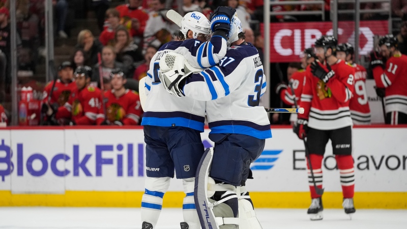 Winnipeg Jets goaltender Connor Hellebuyck (37) and defenseman Brenden Dillon, left, celebrate after their overtime win against the Chicago Blackhawks in an NHL hockey game Friday, Feb. 23, 2024, in Chicago. (AP Photo/Erin Hooley)