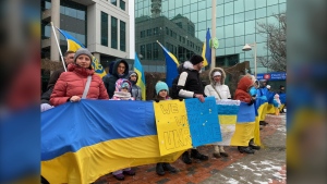 People carry flags and signs in support of Ukraine at Moncton City Hall on Feb. 24, 2024. (CTV/Derek Haggett)