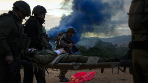 Israeli soldiers run as they carry a stretcher towards a military helicopter during an exercise simulating evacuation of wounded people in northern Israel, near the border with Lebanon, Tuesday, Feb. 20, 2024. (AP Photo/Ariel Schalit)