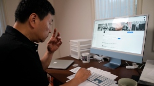 Wang Zhi'an checks his website during an interview with the Associated Press in Tokyo on Oct. 5, 2022. Chinese investigative journalist Wang once exposed corruption, land seizures, and medical malpractice for state broadcaster CCTV. Today, he's in exile in Japan, and starting again as an independent journalist on YouTube. (AP Photo/Eugene Hoshiko)