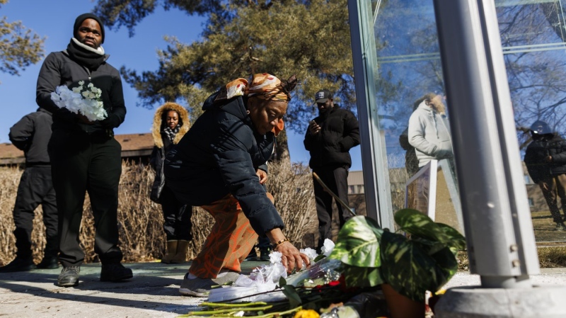 People place flowers at a vigil for Adu Boakye, a man who was fatally shot while waiting for the bus last week near a community centre in Northwest Toronto, Saturday, Feb. 24, 2024. (THE CANADIAN PRESS/Cole Burston)