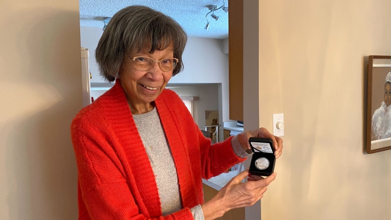 Myrna Wisdom, a descendant of Amber Valley pioneers, holds up a silver commemorative coin honouring her community's history as one of the first all-Black settlements in Western Canada. (Miriam Valdes-Carletti/CTV News Edmonton)