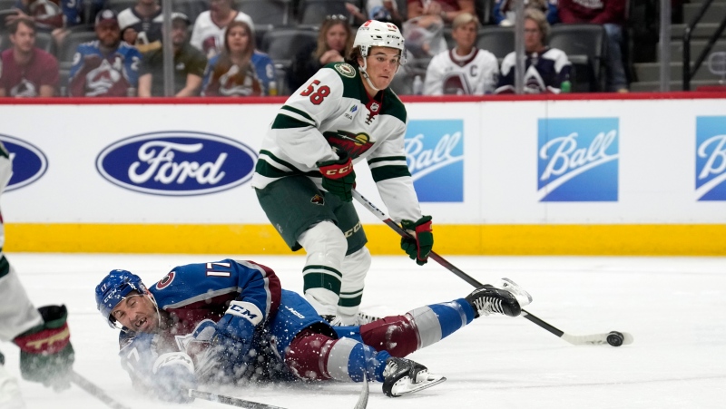 Colorado Avalanche defenseman Brady Hunt, front, tries to stop a shot off the stick of Minnesota Wild center Riley Heidt in the second period of a preseason NHL hockey game, Sunday, Sept. 24, 2023, in Denver. (AP Photo/David Zalubowski)