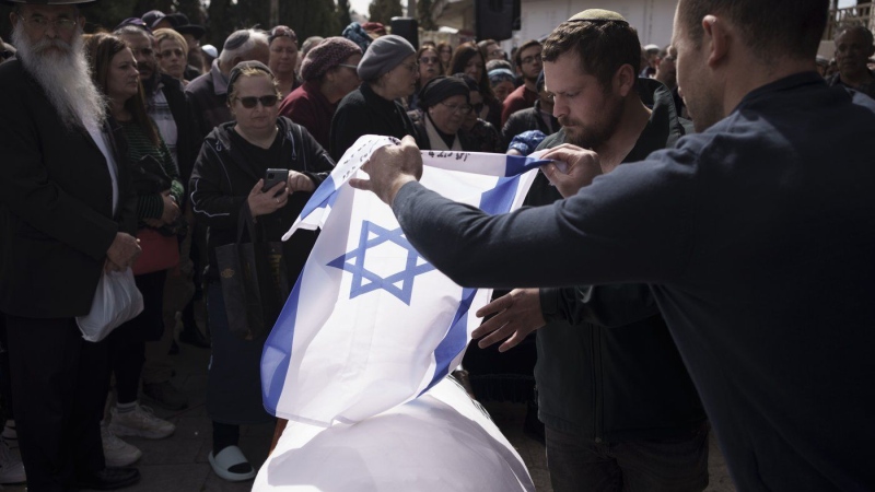 Relatives of Yitzhak Zeiger place an Israeli flag over his body during his funeral at a cemetery in Jerusalem, Israel, Friday, March 1, 2024. (Leo Correa/AP Photo)