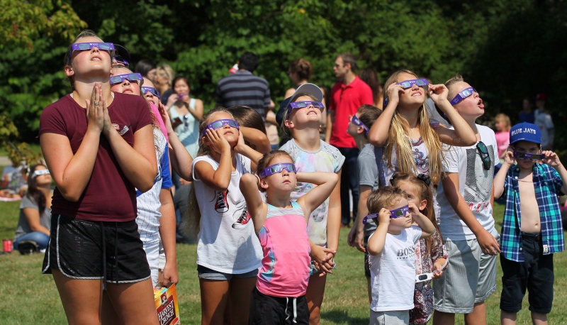 A group of children join hundreds of people gathered at Western University to view the partial solar eclipse, in London, Ont. on Monday, Aug. 21, 2017. (THE CANADIAN PRESS/Dave Chidley)