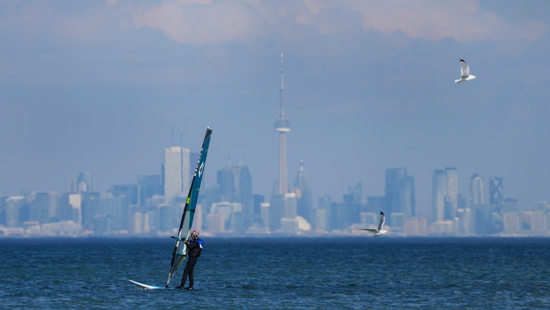 FILE - A windsurfer cuts through the waves along Lake Ontario overlooking the City of Toronto skyline on a warm winter day in Mississauga, Ont., Friday, Feb. 9, 2024. THE CANADIAN PRESS/Nathan Denette 