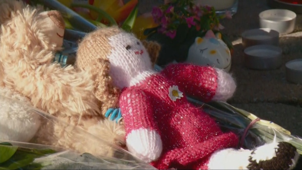 A wool doll rests among the flowers at the base of a memorial at Palmadeo Park in Barrhaven in memory of a mother, her four young children and a family acquaintance killed this week. (Katie Griffin/CTV News Ottawa) 