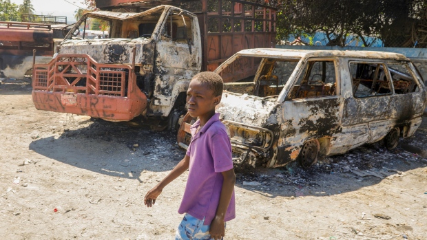 A youth walks by charred cars outside a police station set on fire by armed gangs in Port-au-Prince. (AP Photo/Odelyn Joseph)