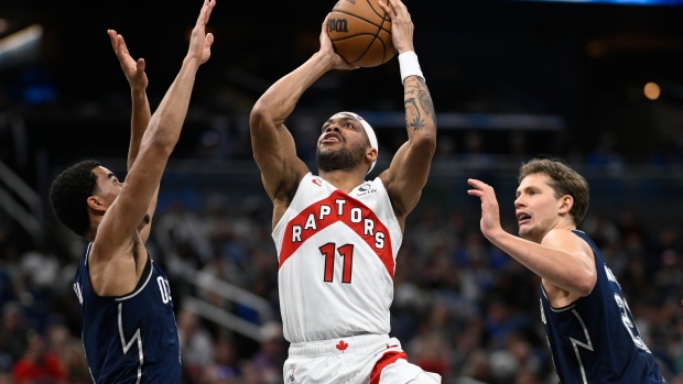 Toronto Raptors forward Bruce Brown (11) goes up to shoot as Orlando Magic guard Caleb Houstan, left, and center Moritz Wagner, right, defend during the second half of an NBA basketball game, Sunday, March 17, 2024, in Orlando, Fla. (AP Photo/Phelan M. Ebenhack) 