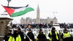 A pro-Palestinian protestor waves a Palestinian flag on Wellington St., as pro-Israel protestors rally on Parliament Hill in Ottawa, on Monday, Dec. 4, 2023. THE CANADIAN PRESS/Spencer Colby