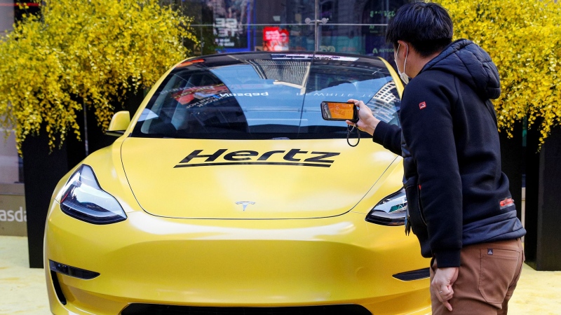 A man photographs a Hertz Tesla electric vehicle displayed during the Hertz Corporation IPO at the Nasdaq Market site in Times Square in New York City. (Brendan McDermid / Reuters via CNN Newsource)