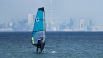 A windsurfer cuts through the waves along Lake Ontario overlooking the City of Toronto skyline on a warm winter day in Mississauga, Ont., Friday, Feb. 9, 2024. THE CANADIAN PRESS/Nathan Denette