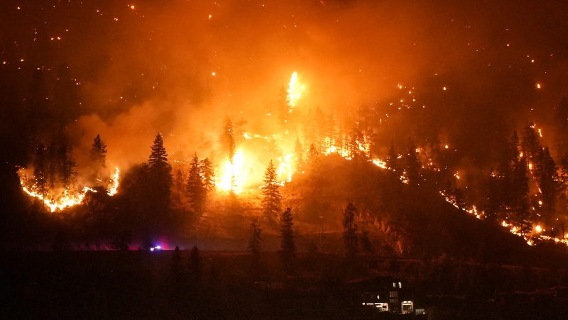 The McDougall Creek wildfire burns on the mountainside above a lakefront home, in West Kelowna, B.C., on Friday, August 18, 2023. (THE CANADIAN PRESS/Darryl Dyck)