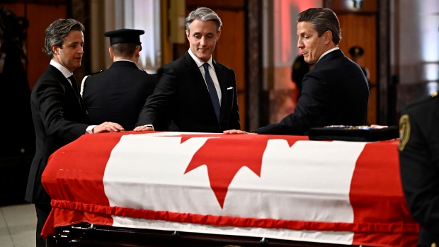 Nicholas, Ben and Mark Mulroney place their hands on the casket of their father, former prime minister Brian Mulroney, as he lies in state at the Sir John A. Macdonald Building, across from Parliament Hill in Ottawa, on Tuesday, March 19, 2024. (Justin Tang/Canadian Press)