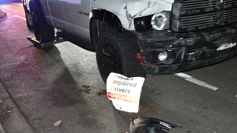 A Dodge Ram is seen next to a "Report Impaired Driving" sign the driver allegedly struck on March 21, 2024. (Handout)