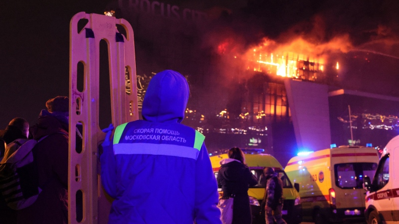 A medic stands near ambulances parked outside the burning building of the Crocus City Hall on the western edge of Moscow, Russia, Friday, March 22, 2024. (Vitaly Smolnikov/AP Photo)