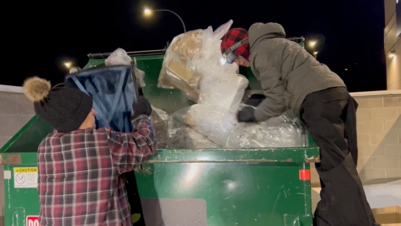 Chelsey Limay and Nicole Favreau search a Saskatoon waste bin for items to reclaim. (Carla Shynkaruk / CTV News)