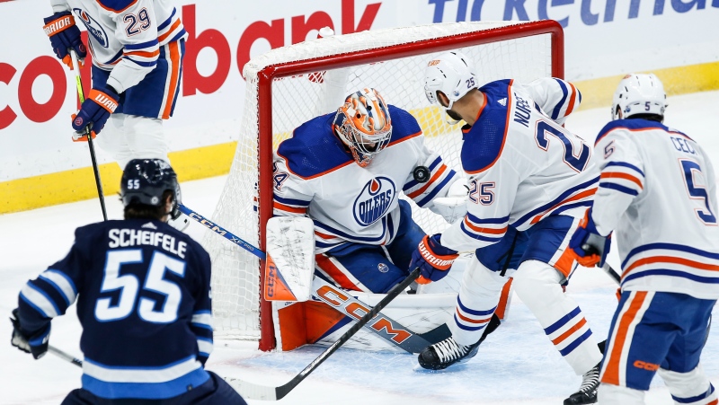 Edmonton Oilers goaltender Stuart Skinner (74) saves the puck that goes off the skate of Darnell Nurse (25) during first period NHL action against the Winnipeg Jets in Winnipeg on Thursday, November 30, 2023. (John Woods/The Canadian Press)