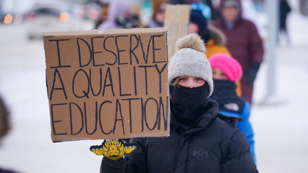 A child holds a sign while walking at a demonstration site during a province-wide, one-day strike organized by the members of the Saskatchewan Teachers’ Federation in Saskatoon, Sask., on Monday, January 22, 2024. THE CANADIAN PRESS/Heywood Yu