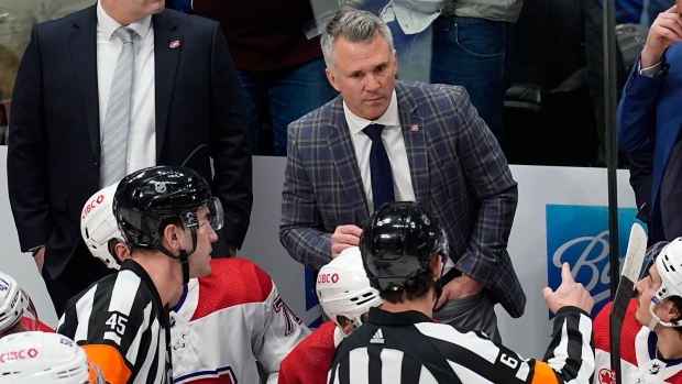 Montreal Canadiens coach Martin St. Louis argues with referees Cody Beach and Francis Charron during the first period of the team's NHL hockey game against the Colorado Avalanche on Tuesday, March 26, 2024, in Denver. (AP Photo/David Zalubowski)