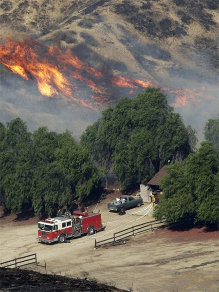 Brush burns behind a house as firefighters prepare to put the fire out in San Francisquito Canyon of Santa Clarita, Calif., north of Los Angeles, Saturday, Oct. 22, 2007. (AP / Kevork Djansezian)