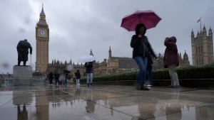 Tourists hold umbrellas against the rain as they walk in Parliament Square next to the the Houses of Parliament in London. (Alastair Grant/AP Photo)