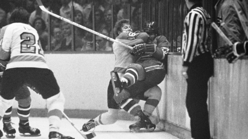 FILE -Philadelphia Flyers center Bobby Clarke (16) pushes Montreal Canadiens defenseman Bob Murdoch (23) into the boards in the third period of an NHL semifinal playoff game, April 22, 1973 in Philadelphia. Bob Murdoch, a two-time Stanley Cup champion and a former NHL defenseman, died at the age of 76, the NHL Alumni Association announced on Friday, Aug. 4, 2023. (AP Photo, File)