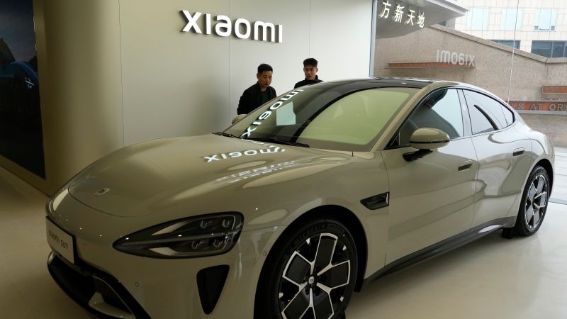Visitors to the Xiaomi Automobile flagship store look at the Xiaomi SU7 electric car on display in Beijing, Tuesday, March 26, 2024. (AP Photo/Ng Han Guan)