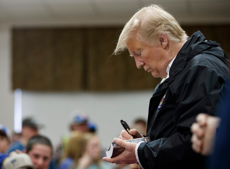 File photo of former U.S. President Donald Trump signing a Bible as he greets people at Providence Baptist Church in Smiths Station, Ala., March 8, 2019, during a tour of areas where tornadoes killed 23 people (Carolyn Kaster / AP Photo)