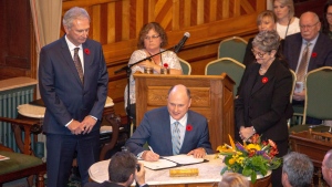 New Brunswick Progressive Conservative MLA Trevor Holder, right, is sworn in as Minister of Post-Secondary Education, Training and Labour at the New Brunswick Legislature in Fredericton on Friday, Nov. 9, 2018. Holder, the province's longest-serving member of legislature, says he will not be running in the upcoming election. (Source: THE CANADIAN PRESS/James West)