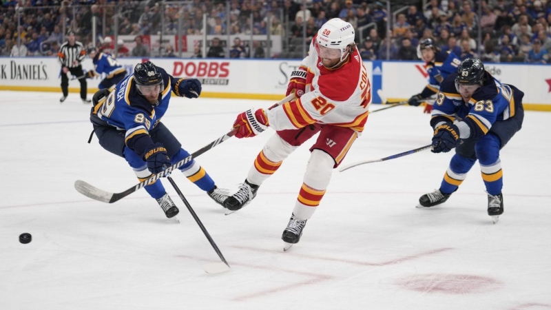 The Calgary Flames' Blake Coleman passes as the St. Louis Blues' Pavel Buchnevich and Jake Neighbours defend on March 28, 2024, in St. Louis. (AP Photo/Jeff Roberson)