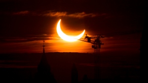 An annular solar eclipse rises over construction cranes and the Peace Tower on Parliament Hill in Ottawa on Thursday, June 10, 2021. THE CANADIAN PRESS/Sean Kilpatrick