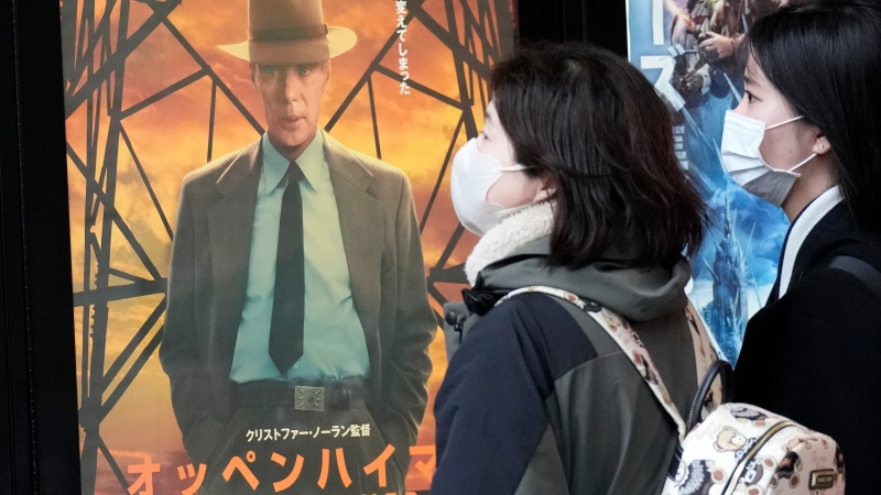 People walk by a poster to promote the movie 'Oppenheimer' on Friday, March 29, 2024, in Tokyo. (AP Photo/Eugene Hoshiko)