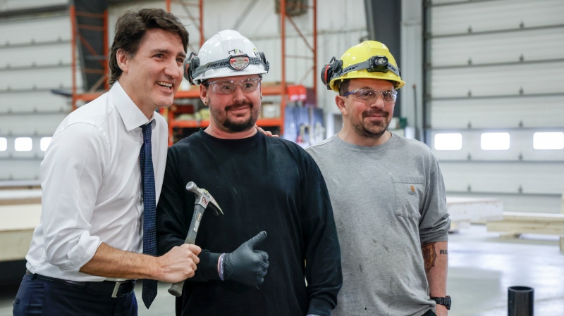 Prime Minister Justin Trudeau, left, poses with employees while he tours a modular home construction facility before making a housing announcement in Calgary, Alta., Friday, April 5, 2024 (Jeff McIntosh / THE CANADIAN PRESS)