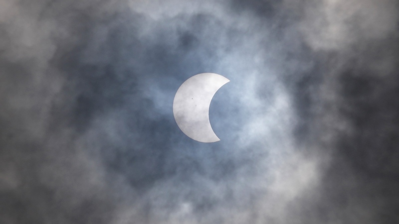 A partial solar eclipse is seen through the clouds over Jakarta, Indonesia, Thursday, April 20, 2023. (AP Photo/Tatan Syuflana)