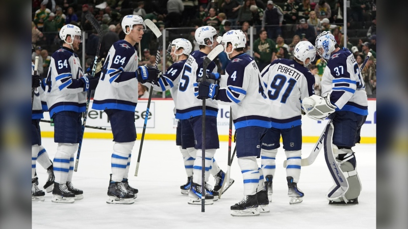 Winnipeg Jets goaltender Connor Hellebuyck (37) celebrates with teammates after they defeated the Minnesota Wild in an NHL hockey game Saturday, April 6, 2024, in St. Paul, Minn. (AP Photo/Abbie Parr)
