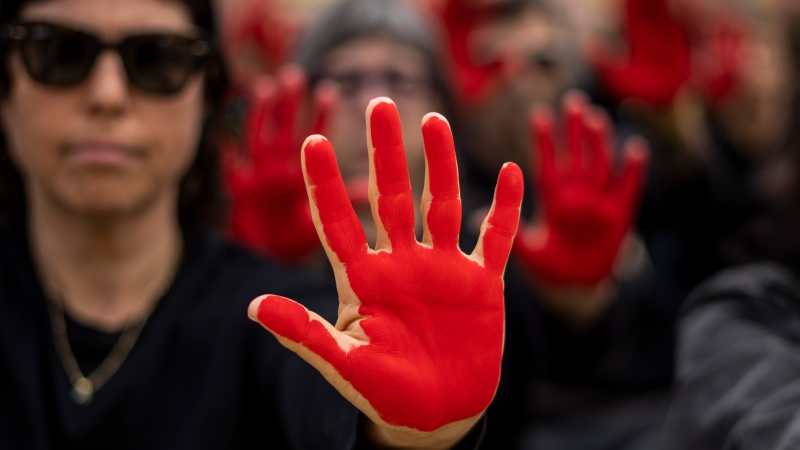 Family and supporters of hostages held in the Gaza Strip hold up their hands, painted red to symbolize blood, to call for the captives' release and to mark six months since the Hamas-led Oct. 7 cross-border attack, in Tel Aviv, Israel, Sunday, April 7, 2024. (AP Photo/Ariel Schalit)