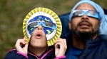 Dezaray Butts and her father Douglas wear solar eclipse glasses as they observe the partial phase of a total solar eclipse, in Kingston, Ont., Monday, April 8, 2024. THE CANADIAN PRESS/Justin Tang