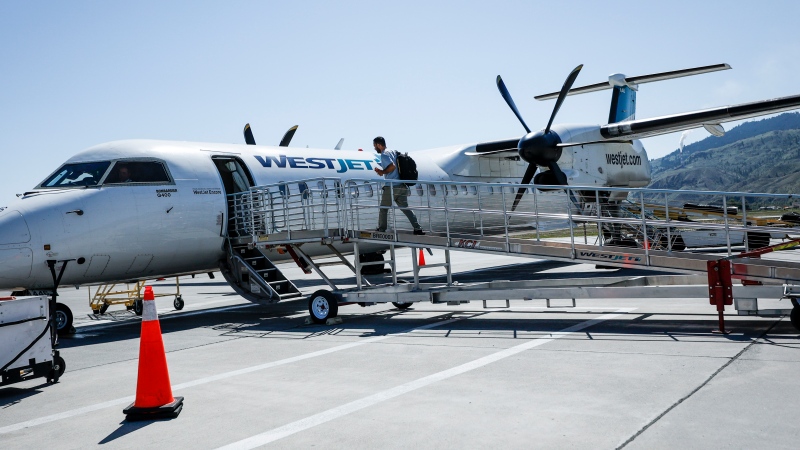 A passenger boards a WestJet Encore Bombardier Q400 twin-engined turboprop aircraft in Kamloops, Saturday, June 3, 2023.THE CANADIAN PRESS/Jeff McIntosh