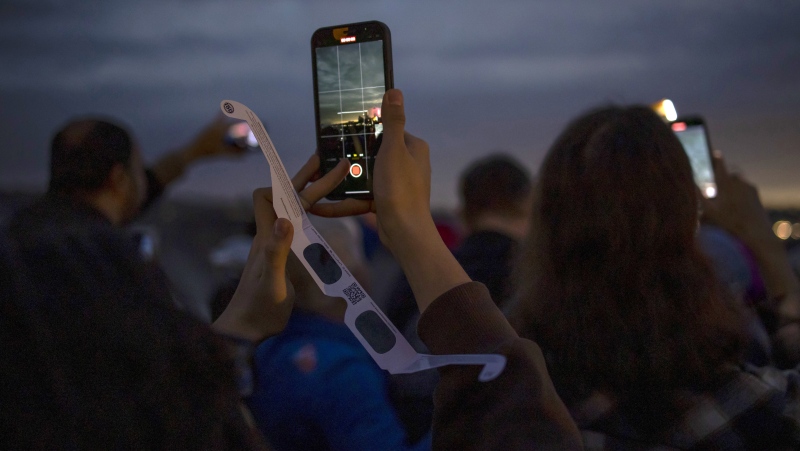 People use their phones to document the total solar eclipse in Niagara Falls, Ont., on Monday, April 8, 2024. THE CANADIAN PRESS/Aaron Lynett