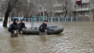 Police officers use a rubber boat as they patrol in the flooded street after part of a dam burst, in Orsk, Russia. State media say Russia's government has declared the situation in flood-hit areas in the Orenburg region a federal emergency. (Anatoly Zhdanov / Kommersant Publishing House via AP)
