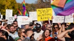 People hold signs while attending a rally against the Saskatchewan government's proposed legislation on pronoun policy in front of Saskatchewan legislature in Regina, on Tuesday, October 10, 2023. (THE CANADIAN PRESS/Heywood Yu)