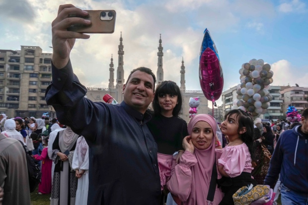 Muslim family members pose for a selfie as they celebrate Eid al-Fitr, marking the end of the Muslim holy fasting month of Ramadan outside al-Seddik mosque in Cairo, Egypt, Wednesday, April 10, 2024. (AP Photo/Amr Nabil)
