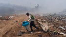 A waste picker walks past clouds of smoke generated by a fire at a garbage dump in Villa Nueva, Guatemala, Tuesday, April 9, 2024. (AP Photo / Moises Castillo)