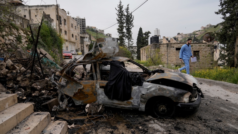 A man passes by a car destroyed in an Israeli army raid in the West Bank Jenin refugee camp on Wednesday, March 27, 2024. (AP Photo / Majdi Mohammed)