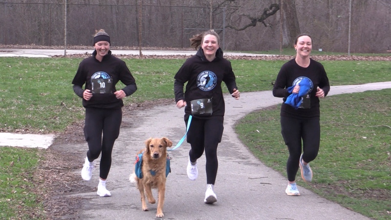 Runners (L-R) Thea Brouwer, Nadia Chylia, and Sidney Robertson cross the finish line with dog Leo at the Marathons for Mental Health 5k run April 13, 2024, at Gibbons Park in London, Ont. (Brent Lale/CTV News London)