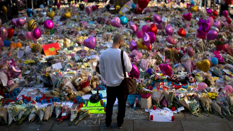 FILE - A man stands next to flowers for the victims of a bombing at St. Ann's Square in central Manchester, England, May 26, 2017. More than 250 survivors of the suicide bombing are taking legal action against Britain's domestic intelligence agency, lawyers said April 14, 2024. (AP Photo/Emilio Morenatti, File)